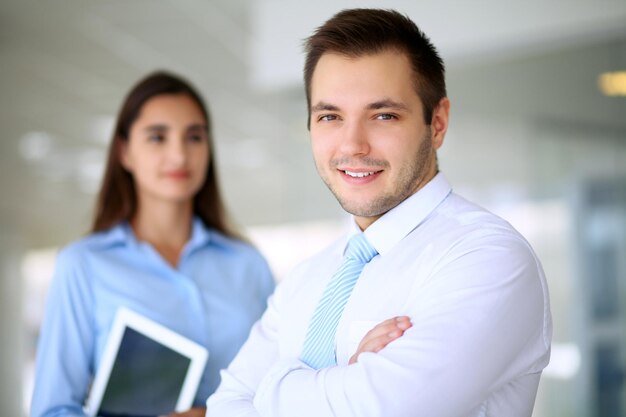 Empresario sonriente en la oficina con colegas en el fondo