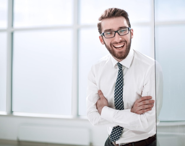 Empresario sonriente de pie cerca de la ventana de la oficina