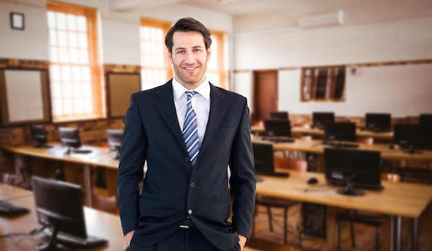 Empresario sonriente de pie con las manos en los bolsillos contra la sala de ordenadores