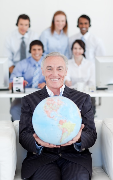 Empresario sonriente sosteniendo un globo terrestre