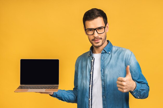 Foto empresario sonriente sosteniendo la pantalla del portátil en blanco mirando a la cámara thumbs up