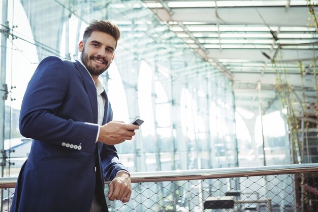 Empresario sonriente a través de teléfono móvil en la estación de tren