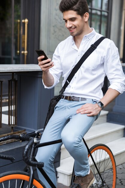 Empresario sonriente vestido con camisa sentado en una bicicleta