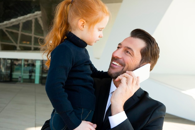 Empresário sorridente ao telefone segurando a filha