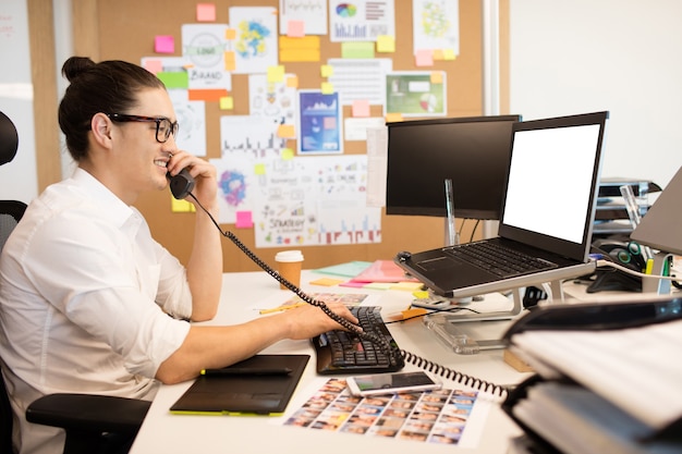 Empresário sorridente falando ao telefone no escritório criativo