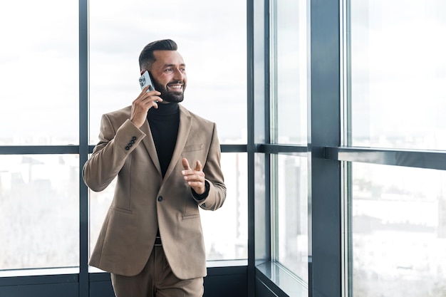 Empresário sorridente falando no celular enquanto caminhava no escritório