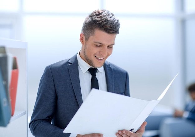 Empresário sorridente lendo alguns documentos no local de trabalho