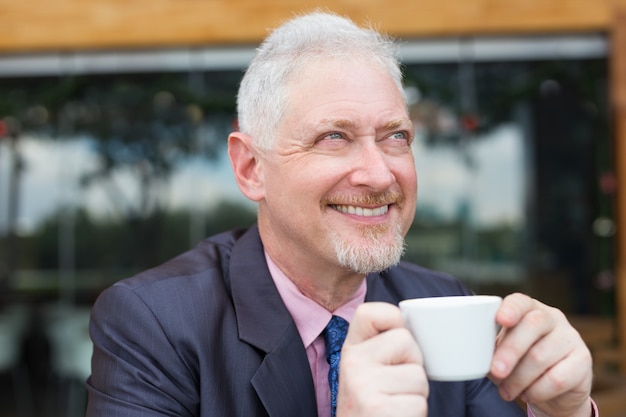 Empresário sorridente que bebe café ao ar livre