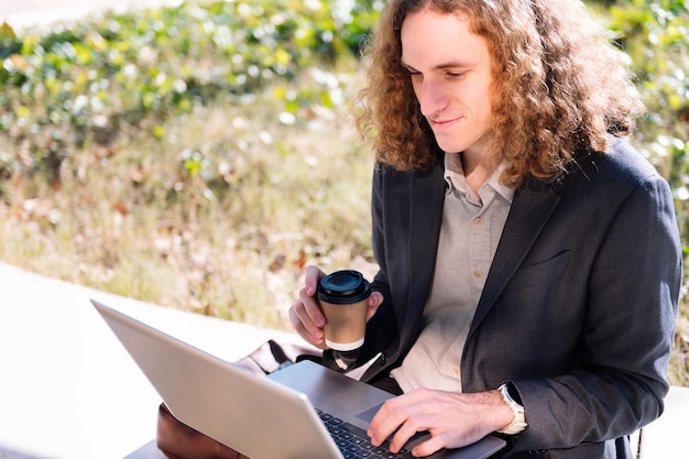 Empresário sorridente trabalhando ao ar livre com um laptop