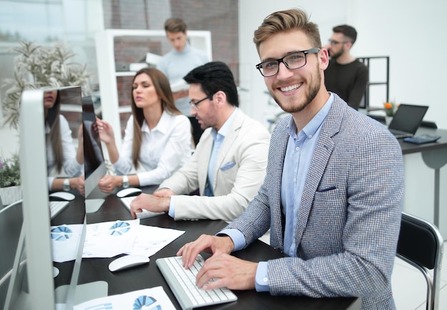 Empresário sorridente usa um computador para analisar dados financeiros o conceito de profissionalismo