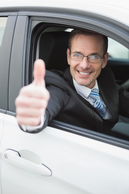 Empresário sorrindo na câmera mostrando polegares para cima