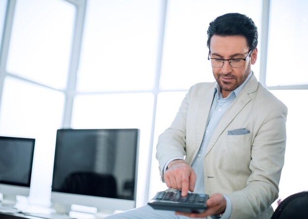 Empresario sosteniendo una calculadora mientras está sentado en su concepto Deskbusiness