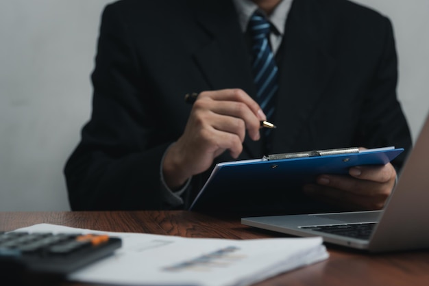 Empresario sosteniendo un documento de firma de pluma en el portapapeles en el escritorio Abogado de seguros de información comercial y concepto de trabajo