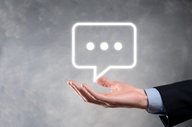 Empresario sosteniendo un icono de mensaje, señal de notificación de conversación de burbujas en sus manos. Icono de chat, icono de sms, icono de comentarios, burbujas de voz