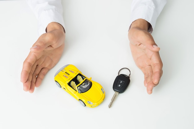 Empresario sosteniendo las llaves de un auto y un modelo de auto en miniatura