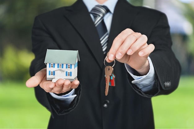Empresario sosteniendo modelo de casa y llaves, concepto de bienes raíces