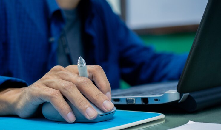 Foto empresario sosteniendo la pluma y usando el control del mouse en la computadora portátil del ordenador portátil en el trabajo