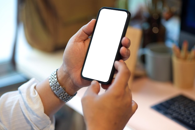 Empresario sosteniendo smartphone, usando smartphone en su escritorio de oficina. pantalla en blanco del teléfono. de cerca