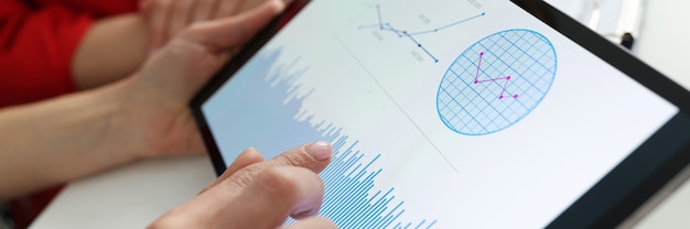 Empresario sosteniendo tableta con gráficos y diagramas en sus manos en el lugar de trabajo empresarial