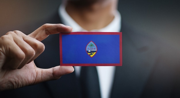 Foto empresario sosteniendo la tarjeta de bandera de guam