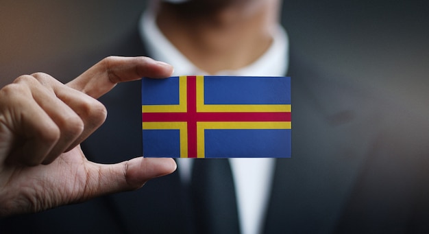 Empresario sosteniendo la tarjeta de bandera de las islas Aland