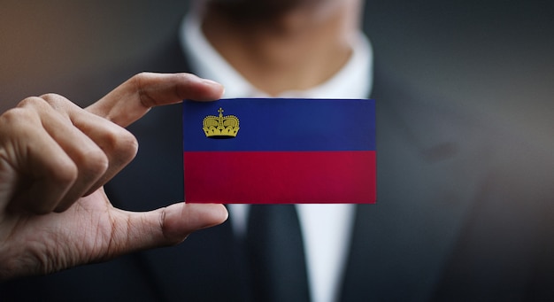 Empresario sosteniendo la tarjeta de bandera de Liechtenstein