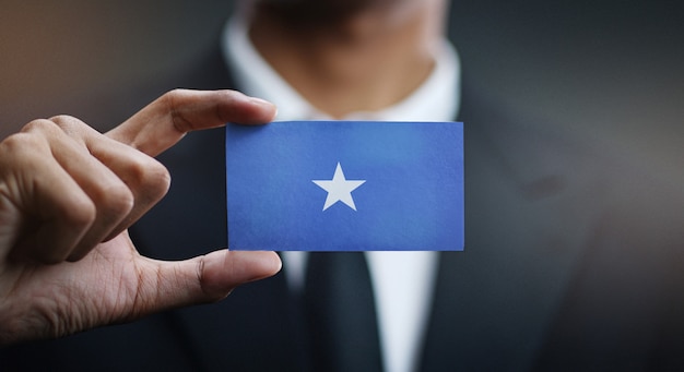 Foto empresario sosteniendo la tarjeta de la bandera de somalia