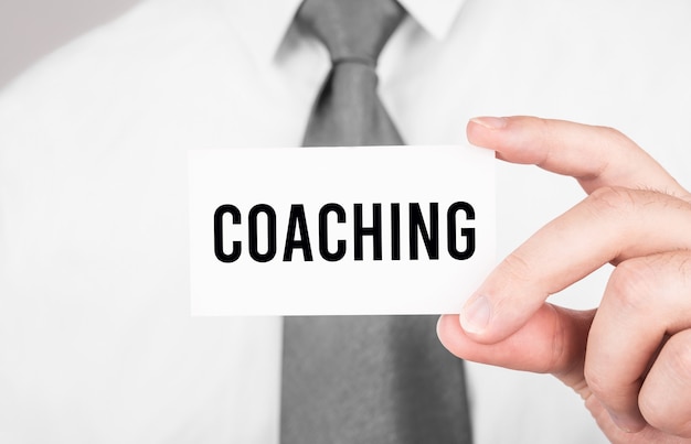 Empresario sosteniendo una tarjeta con texto Coaching, concepto de negocio