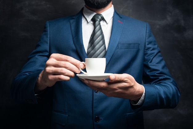 Empresario sosteniendo una taza de café sobre una superficie oscura