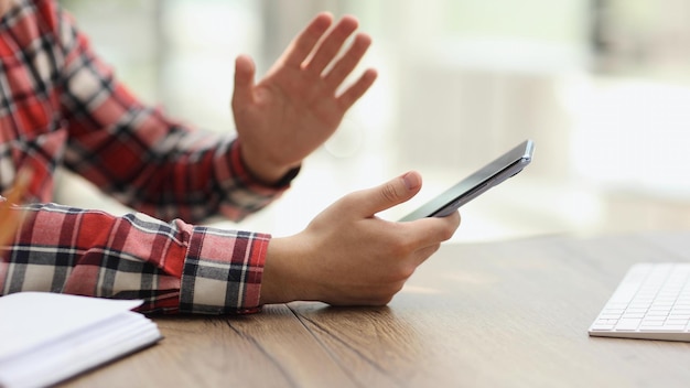 Empresario sosteniendo un teléfono inteligente sentado en la oficina trabajando en línea en un gadget