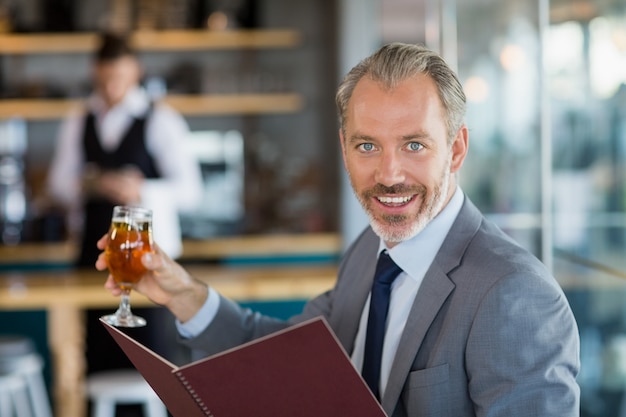 Empresario sosteniendo un vaso de cerveza y menú