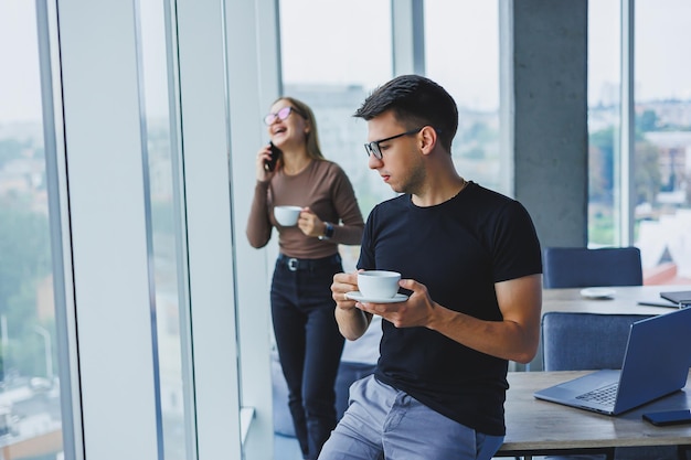 Empresario sostiene una taza de café en la mano Concepto multitarea Freelancer ocupado en vasos bebiendo té y hablando en un café elegante informal