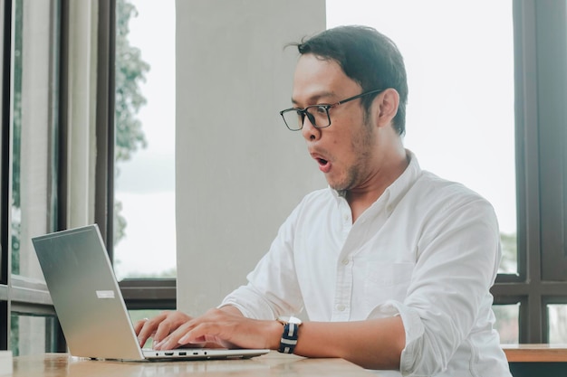 Empresário surpreso olhando para a tela do laptop trabalhador de escritório masculino sofrendo problemas de negócios enquanto trabalhava on-line no computador no escritório