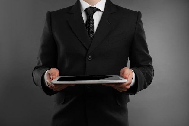 Empresario con tableta sobre fondo gris