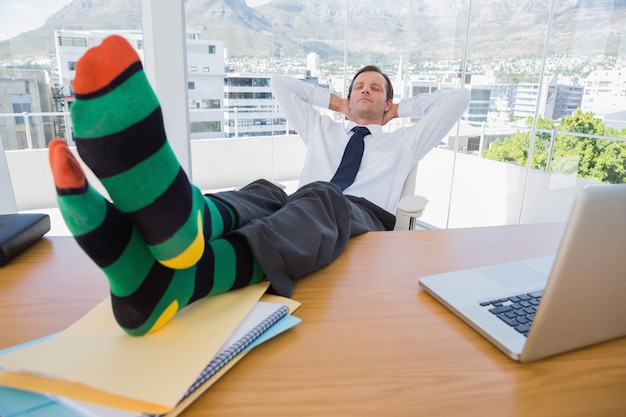 Empresario tener una siesta con los pies en el escritorio