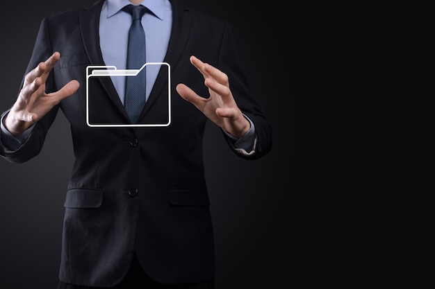 El empresario tiene un icono de carpeta. El sistema de gestión de documentos o la configuración de DMS por parte de un consultor de TI con una computadora moderna están buscando información de gestión y archivos corporativos. Procesamiento de negocios,
