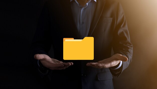 El empresario tiene un icono de carpeta. El sistema de gestión de documentos o la configuración de DMS por parte de un consultor de TI con una computadora moderna están buscando información de gestión y archivos corporativos. Procesamiento de negocios,