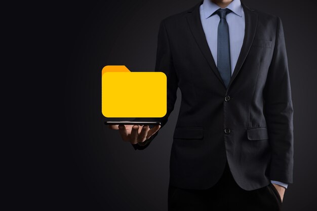 El empresario tiene un icono de carpeta. El sistema de gestión de documentos o la configuración de DMS por parte de un consultor de TI con una computadora moderna están buscando información de gestión y archivos corporativos. Procesamiento de negocios,
