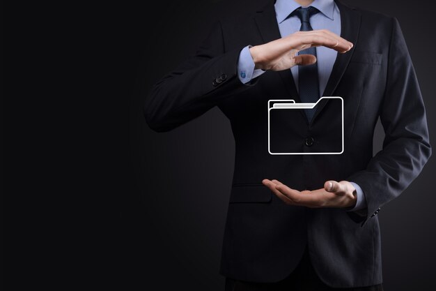 El empresario tiene un icono de carpeta. El sistema de gestión de documentos o la configuración de DMS por parte de un consultor de TI con una computadora moderna están buscando información de gestión y archivos corporativos. Procesamiento de negocios,