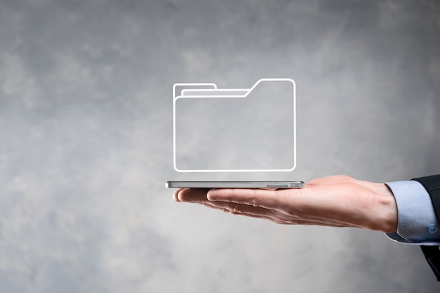El empresario tiene un icono de carpeta. El sistema de gestión de documentos o la configuración de DMS por parte de un consultor de TI con una computadora moderna están buscando información de gestión y archivos corporativos. Procesamiento de negocios,