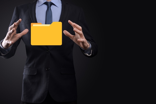 El empresario tiene un icono de carpeta. El sistema de gestión de documentos o la configuración de DMS por parte de un consultor de TI con una computadora moderna están buscando información de gestión y archivos corporativos. Procesamiento de negocios,