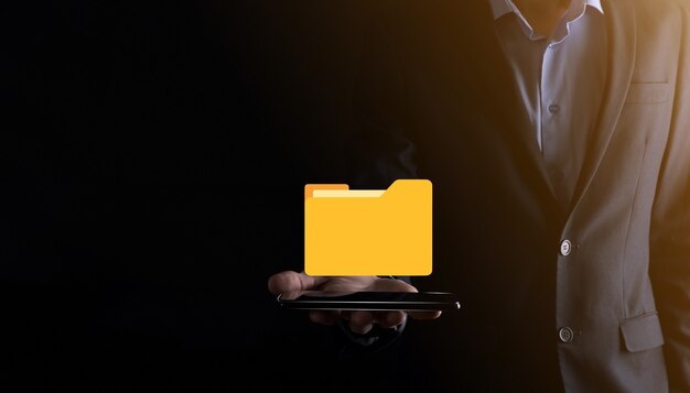 El empresario tiene un icono de carpeta. El sistema de gestión de documentos o la configuración de DMS por parte de un consultor de TI con una computadora moderna están buscando información de gestión y archivos corporativos. Procesamiento de negocios,