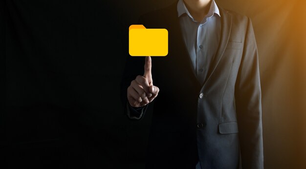 El empresario tiene un icono de carpeta. El sistema de gestión de documentos o la configuración de DMS por parte de un consultor de TI con una computadora moderna están buscando información de gestión y archivos corporativos. Procesamiento de negocios,