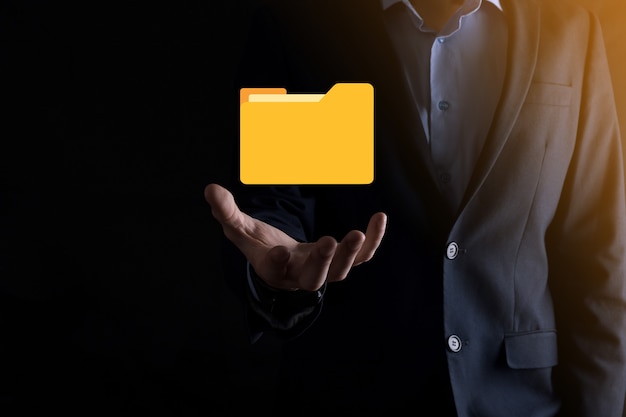 El empresario tiene un icono de carpeta. El sistema de gestión de documentos o la configuración de DMS por parte de un consultor de TI con una computadora moderna están buscando información de gestión y archivos corporativos. Procesamiento de negocios,