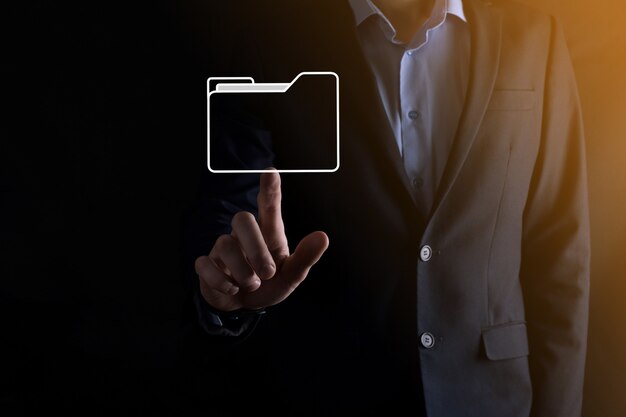 El empresario tiene un icono de carpeta. El sistema de gestión de documentos o la configuración de DMS por parte de un consultor de TI con una computadora moderna están buscando información de gestión y archivos corporativos. Procesamiento de negocios,