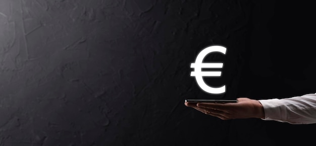 El empresario tiene los iconos de monedas de dinero EUR o Euro sobre fondo de tono oscuro.Creciente concepto de dinero para la inversión empresarial y las finanzas