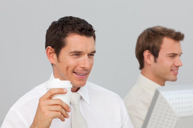 Empresario tomando café en la oficina mientras él está usando la computadora