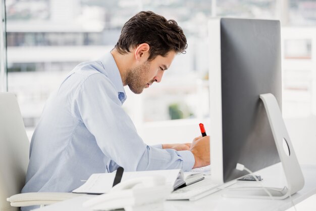 Empresario tomando notas en su escritorio