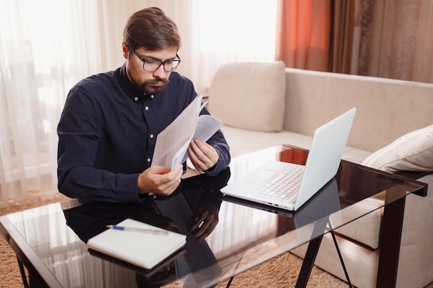 El empresario trabaja con una computadora portátil y guarda un documento en una oficina en casa