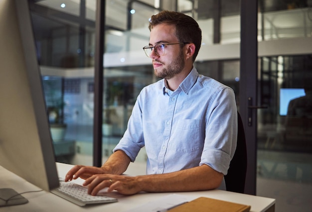 Foto empresario trabajador nocturno y planificación informática trabajando y escribiendo en línea propuesta de proyecto correo electrónico o informe comercial centrarse en el sitio web de escritorio para empleados jóvenes e ideas estratégicas en una agencia de marketing oscura